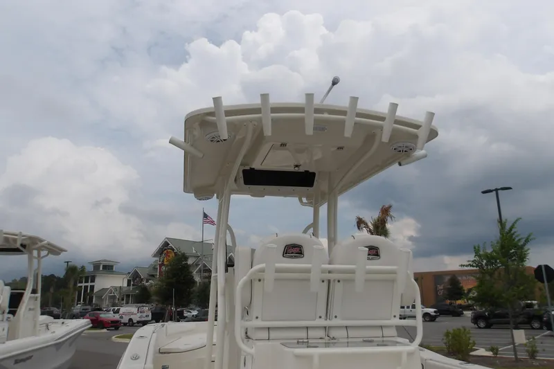 Slide: The Image of 2025 Ranger 2660 Bay boat with T-top and rod holders, parked outdoors. - 14