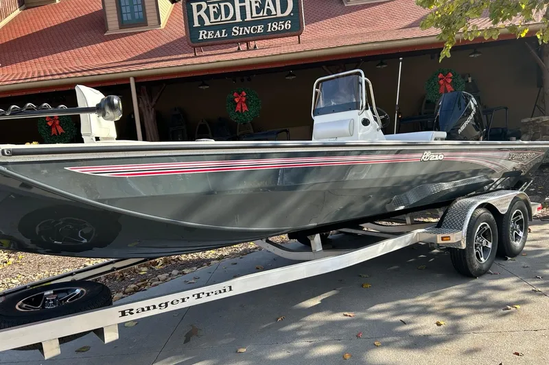 The Image of 2025 Ranger RB210 boat on trailer, parked outside RedHead store with holiday wreaths. - 0
