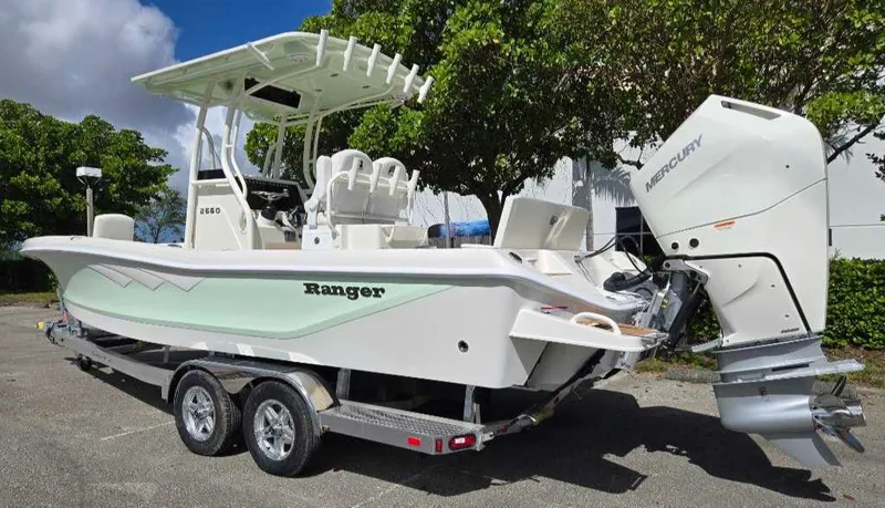 Slide: The Image of 2025 Ranger 2660 Bay boat with Mercury engine on trailer, parked outdoors. - 7