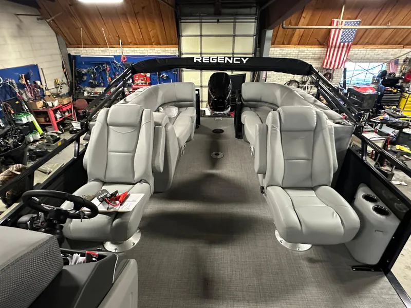 Slide: The Image of 2025 Regency 230 DL3 boat interior with gray seating in a workshop setting. - 10
