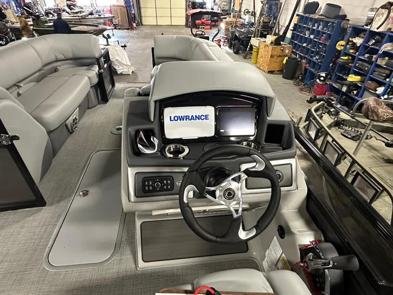 Slide: The Image of 2025 Regency 230 DL3 boat interior with steering console and Lowrance display in a workshop. - 12