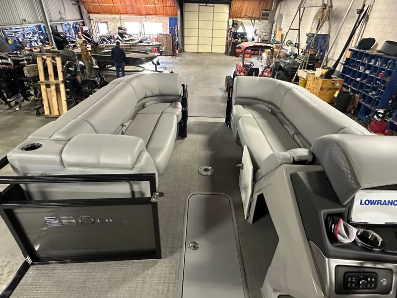 Slide: The Image of 2025 Regency 230 DL3 pontoon boat interior with gray seating in a workshop. - 13