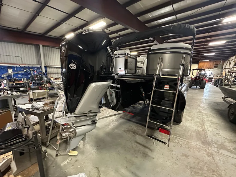 Slide: The Image of 2025 Regency 230 DL3 pontoon boat in a workshop, featuring a powerful outboard motor. - 5