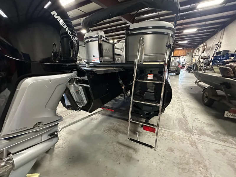 Slide: The Image of 2025 Regency 230 DL3 pontoon boat in a warehouse, featuring a Mercury engine and ladder. - 6