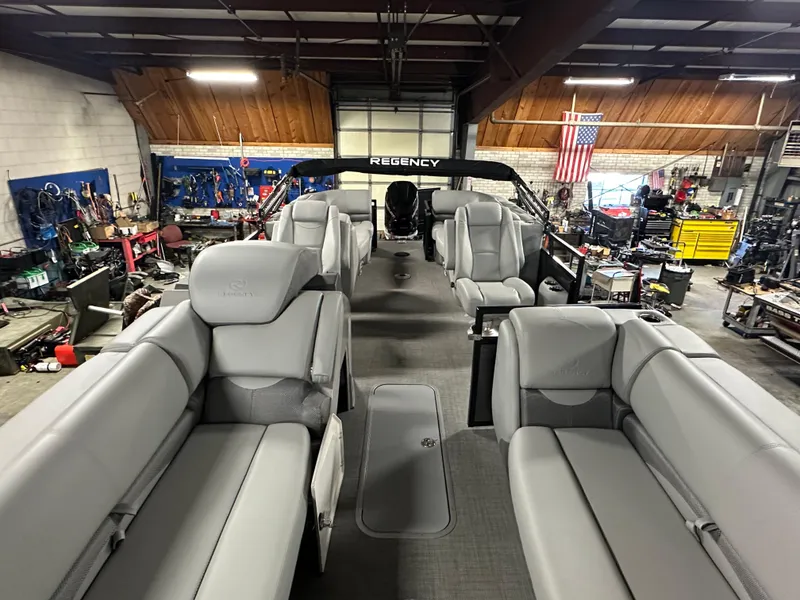 Slide: The Image of 2025 Regency 230 DL3 pontoon boat interior with gray seating in a workshop. - 9