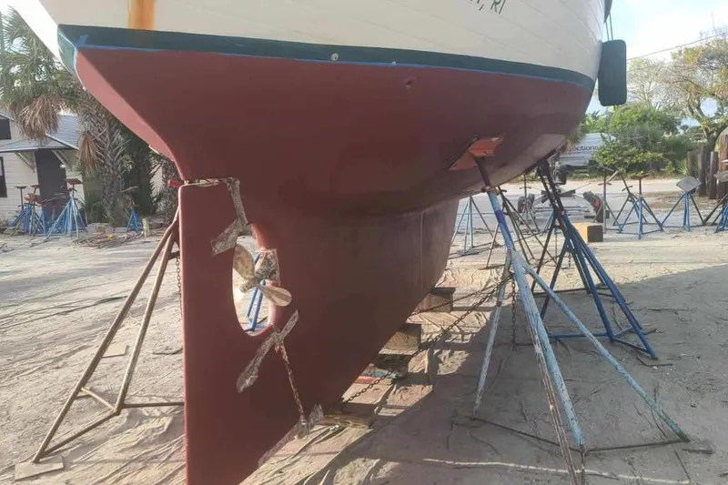 Slide: The Image of 1985 Tayana 37 sailboat on stands, showing hull and propeller in a boatyard. - 27