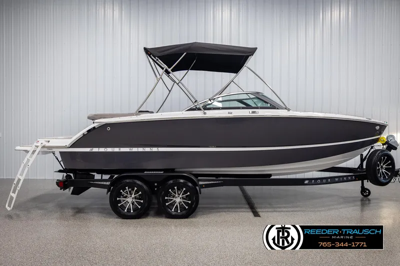 Slide: The Image of 2025 Four Winns H2 boat on trailer in showroom, featuring sleek design and canopy. - 5