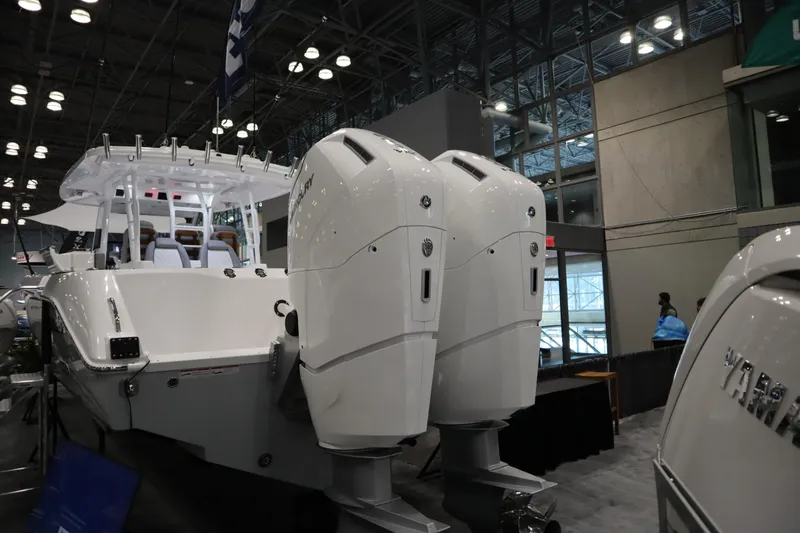 Slide: The Image of 2025 Everglades 395 Center Console boat with dual outboard engines at an indoor exhibition. - 2