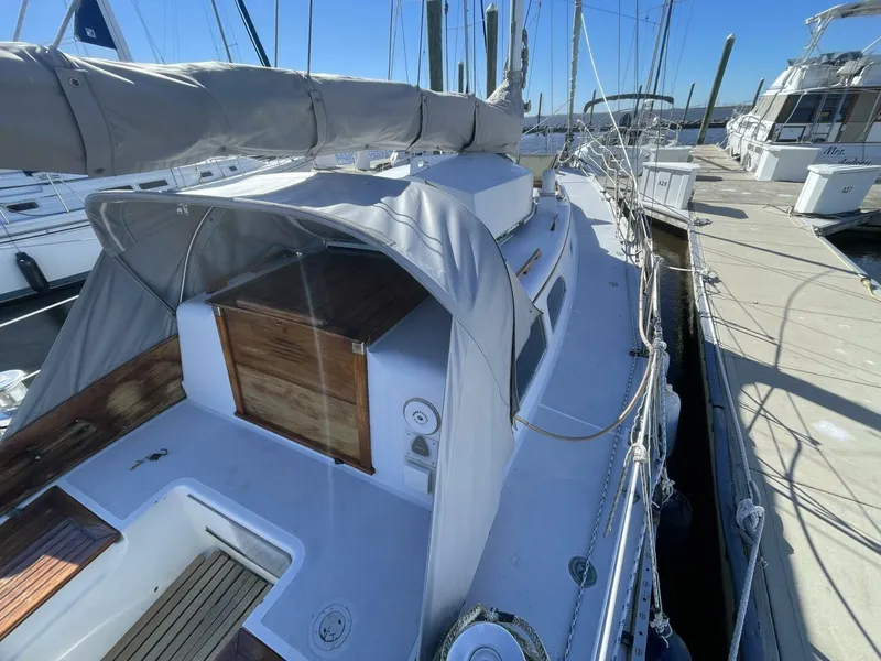 Slide: The Image of 1968 LeComte Northeast 38 sailboat docked, featuring covered cockpit and wooden hatch. - 11