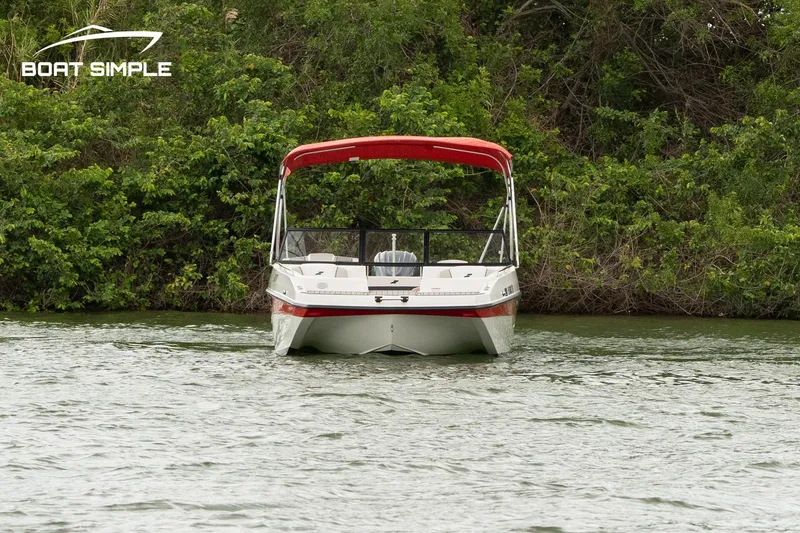 Slide: The Image of 2024 Starcraft SVX 190 OB DC boat on water with red canopy, lush greenery background. - 1
