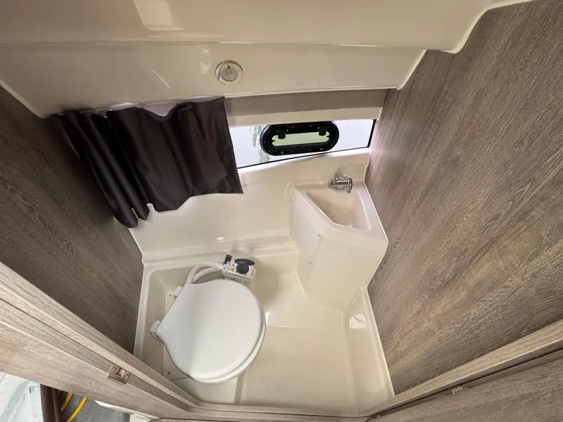 Slide: The Image of 2025 Trophy T25 Explorer bathroom with toilet, sink, and window. Compact marine design. - 7