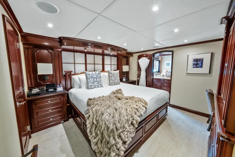 Slide: The Image of Luxurious bedroom on 2005 Trinity Yachts Tri-Deck with elegant wood furnishings and plush bedding. - 22