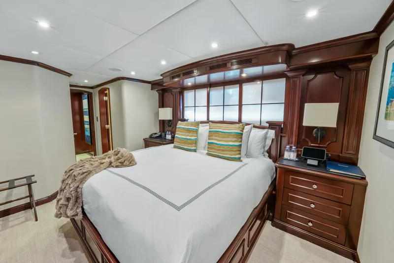 Slide: The Image of Luxurious bedroom interior on 2005 Trinity Yachts Tri-Deck, featuring elegant wood furnishings and cozy bedding. - 23