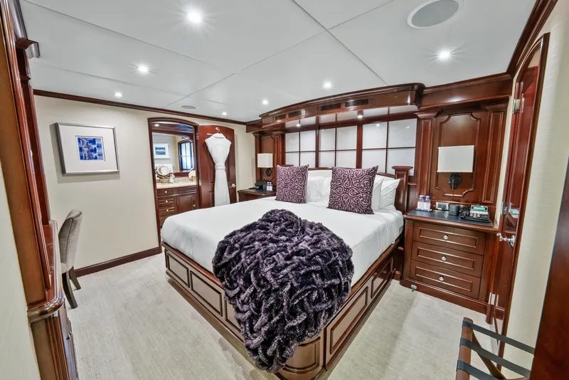 Slide: The Image of Luxurious bedroom on 2005 Trinity Yachts Tri-Deck with elegant wood furnishings and plush bedding. - 26