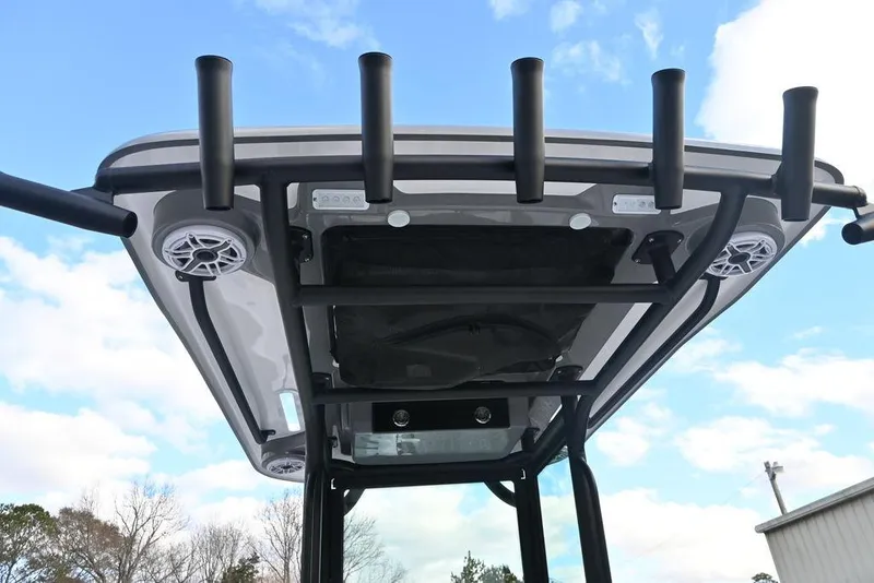 Slide: The Image of 2025 Caymas 26 HB boat T-top with rod holders and speakers against blue sky. - 18