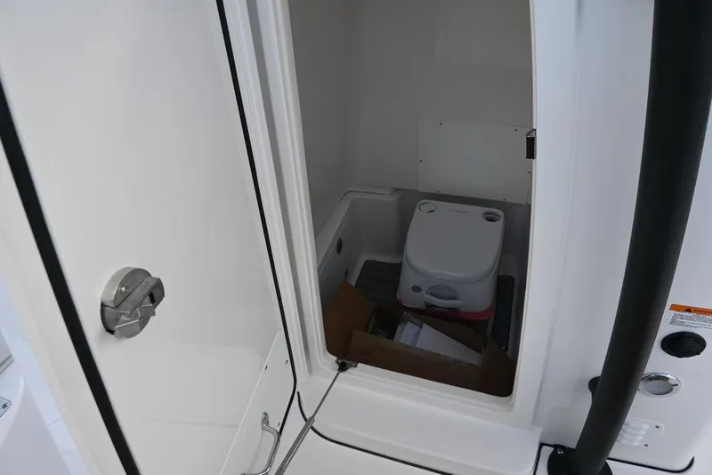 Slide: The Image of 2025 Caymas 26 HB boat interior storage compartment with portable toilet. - 27