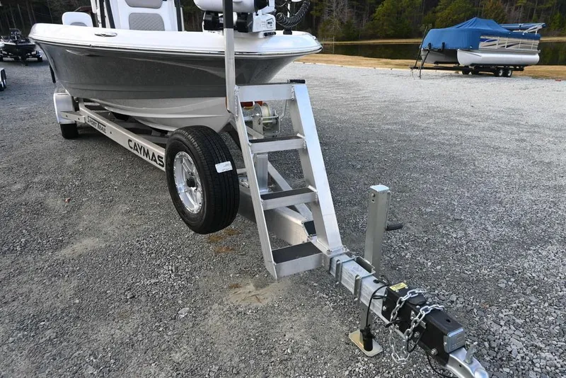 Slide: The Image of 2025 Caymas 26 HB boat on trailer, parked on gravel lot. - 6