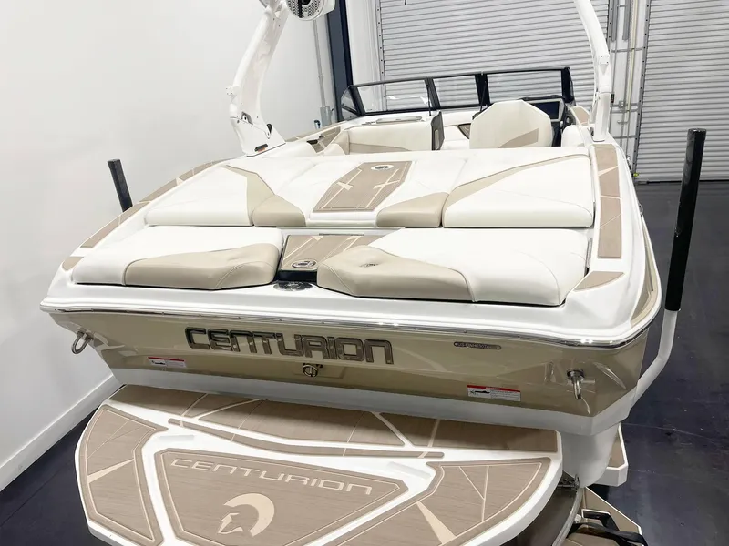 Slide: The Image of 2025 Centurion NV213 boat with beige and white seating, rear view in a showroom. - 5