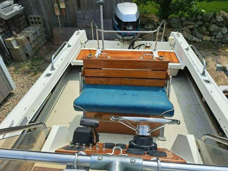Slide: The Image of 1973 Boston Whaler 21 Outrage boat interior with wooden bench and V6 engine. - 10