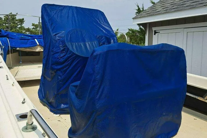 Slide: The Image of 1973 Boston Whaler 21 Outrage boat with blue protective covers, docked near a shed. - 13