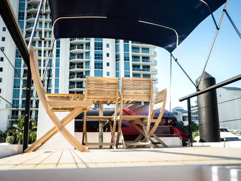 Slide: The Image of 2024 Navisyo Homes 28' NAVIS V.08 yacht deck with wooden chairs, cityscape background. - 17