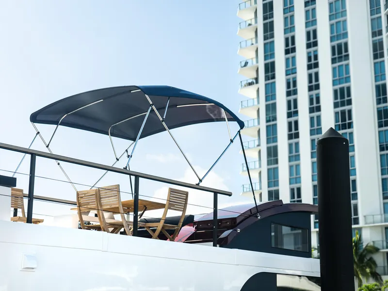 Slide: The Image of 2024 Navisyo Homes 28' NAVIS V.08 yacht with canopy and chairs, cityscape background. - 18