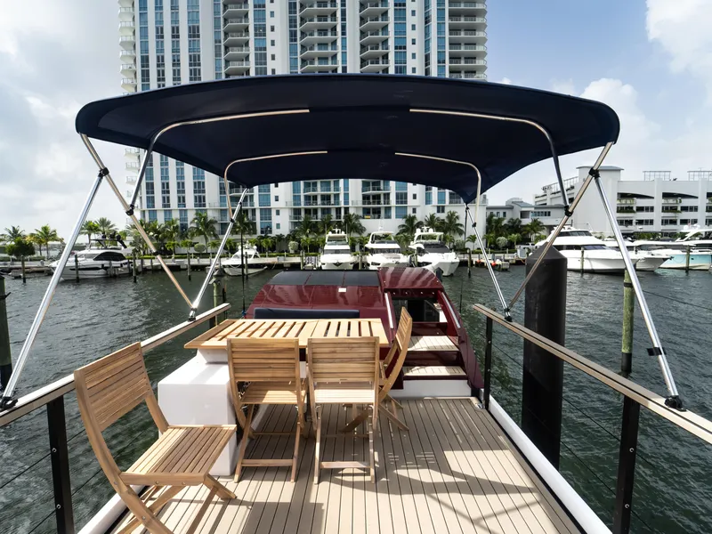 Slide: The Image of 2024 Navisyo Homes 28' NAVIS V.08 boat with canopy and seating, docked near waterfront buildings. - 27