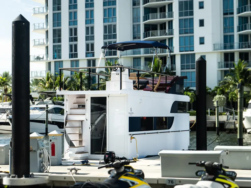 Slide: The Image of 2024 Navisyo Homes 28' NAVIS V.08 houseboat docked in marina, modern building backdrop. - 12