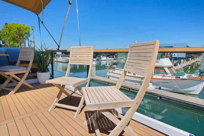 Slide: The Image of Modern 2024 Navisyo Homes 28' NAVIS V.08 houseboat deck with wooden chairs and marina view. - 6