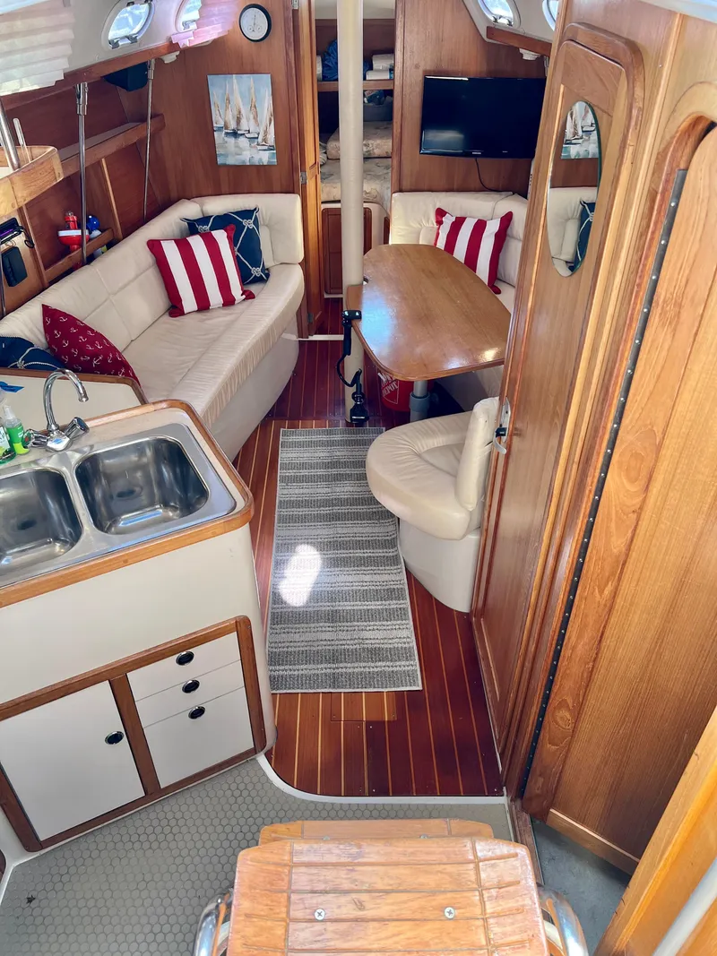 Slide: The Image of Interior of a 2000 Catalina 320 sailboat with cozy seating and wooden finishes. - 30