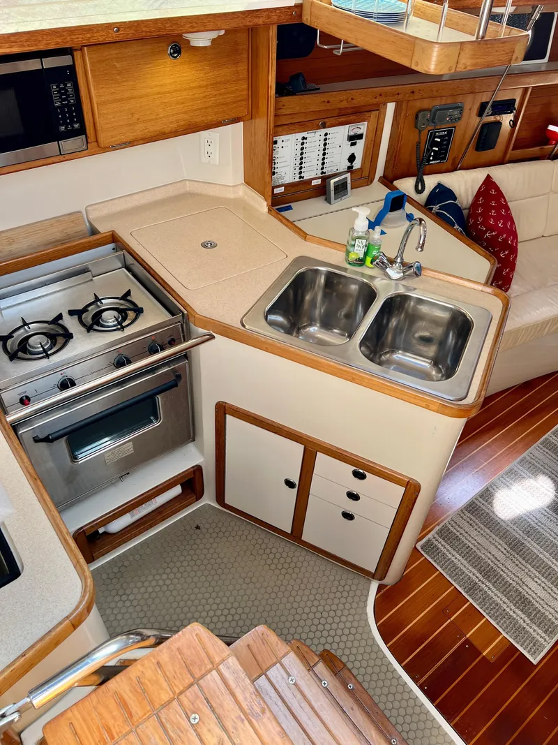 Slide: The Image of Compact kitchen in a 2000 Catalina 320 sailboat with stove, sink, and wooden cabinetry. - 31