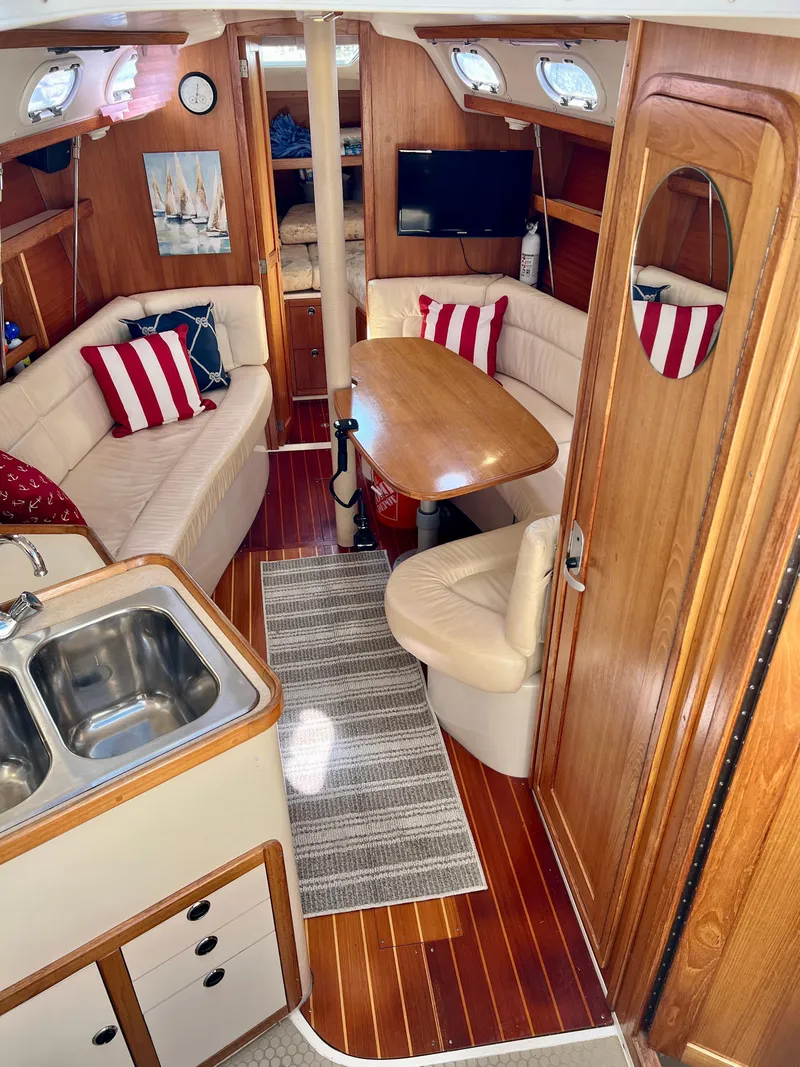 Slide: The Image of Interior of a 2000 Catalina 320 sailboat with cozy seating and wooden finishes. - 32