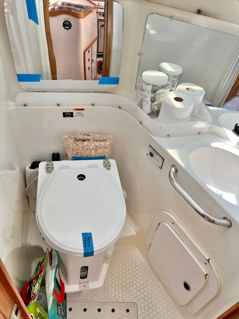 Slide: The Image of Compact bathroom in a 2000 Catalina 320 sailboat, featuring a toilet and sink. - 49