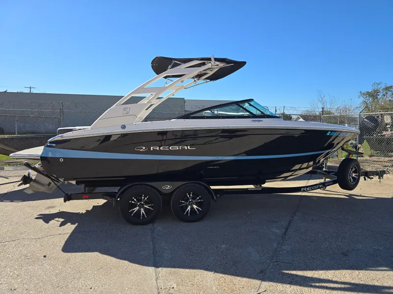 Slide: The Image of 2021 Regal LS2 boat on trailer, sleek black design, parked outdoors. - 17