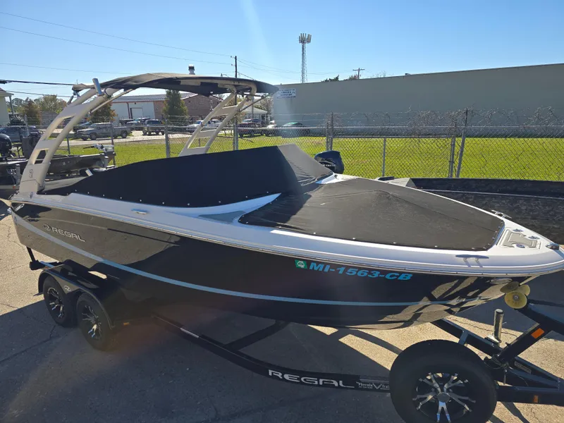 Slide: The Image of 2021 Regal LS2 boat on trailer, parked outdoors in sunny weather. - 2