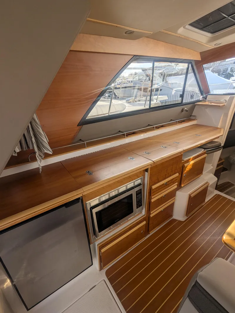 Slide: The Image of 2022 Cutwater C-32 CB yacht interior kitchen with wood finish and modern appliances. - 37