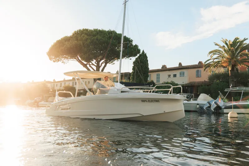 Slide: The Image of 2025 Axopar AX/E 25 electric boat with EVOY® STORM engines cruising near city skyline. - 2