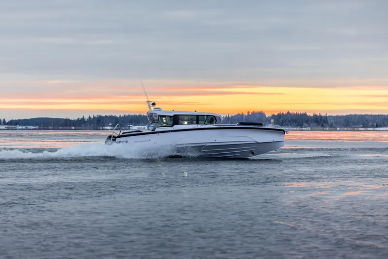 Slide: The Image of 2025 Axopar 29 XC boat cruising on water at sunset. - 18