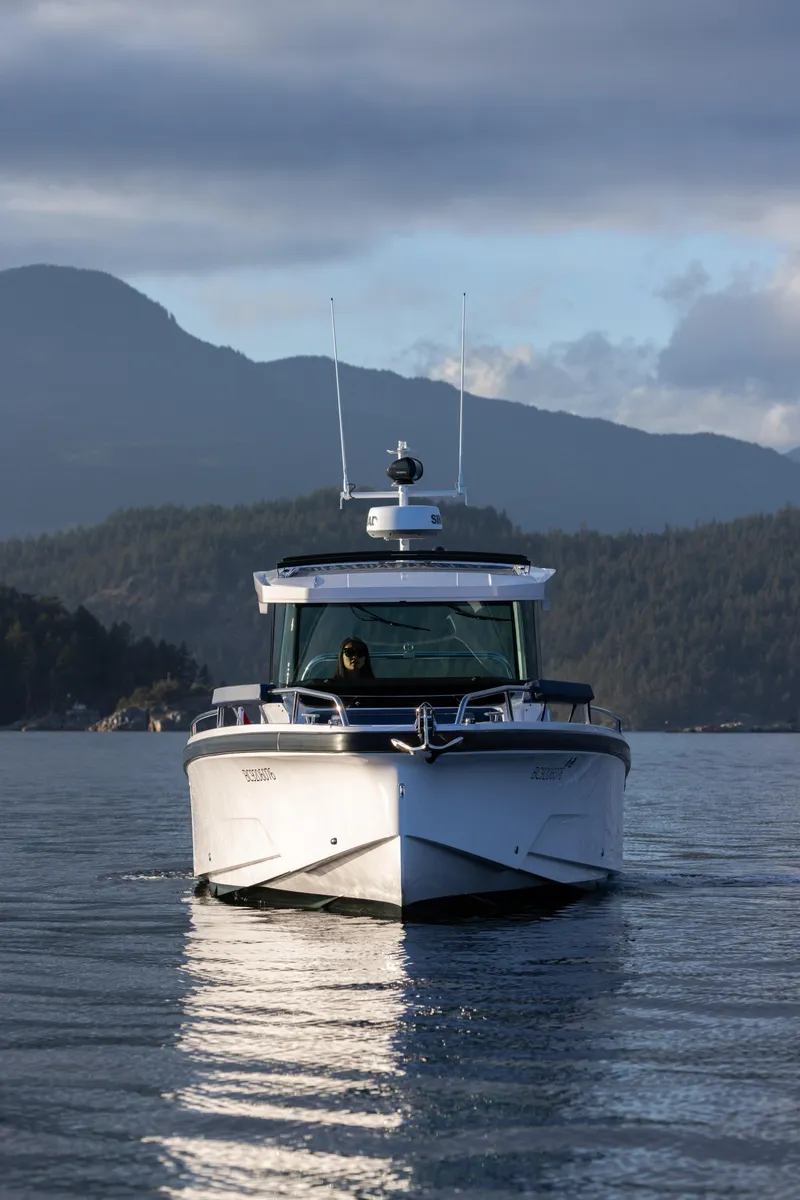 Slide: The Image of 2025 Axopar 29 XC boat cruising on calm water with mountainous backdrop. - 3
