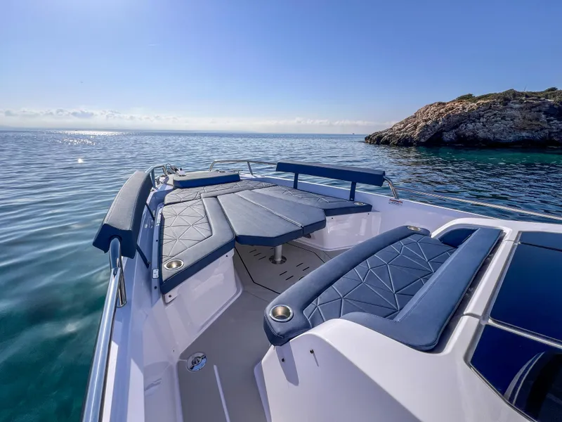 Slide: The Image of 2025 Axopar 29 XC boat with luxurious seating, cruising near a rocky coastline. - 5