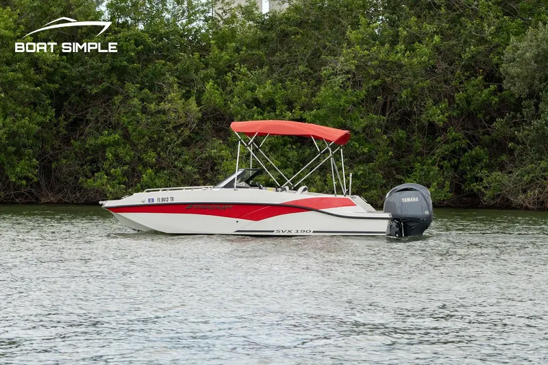 Slide: The Image of 2024 Starcraft SVX 190 OB DC boat with red canopy on a calm lake. - 0