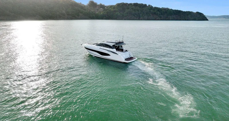 Slide: The Image of 2019 Princess V50 yacht cruising on serene waters near a lush coastline. - 10