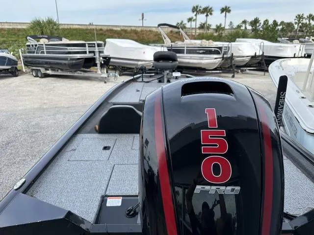 Slide: The Image of 2024 Tracker PROTEAM 195 TXW boat with 150 Pro engine, parked near other boats. - 11