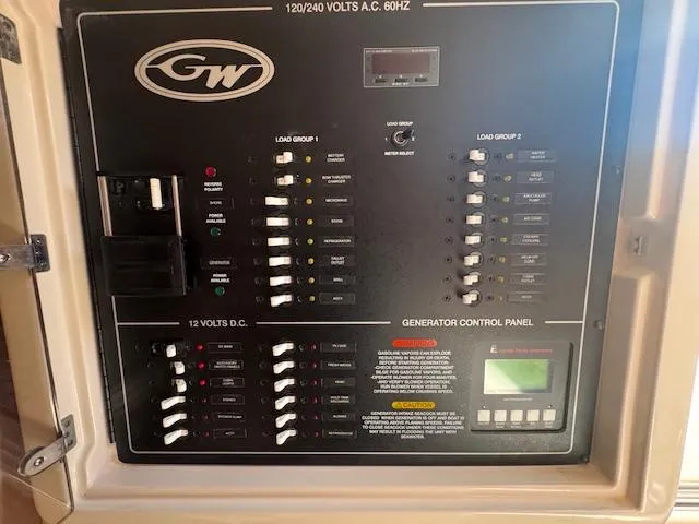 Slide: The Image of Grady-White Express 370 2021 electrical control panel with generator controls and circuit breakers. - 19