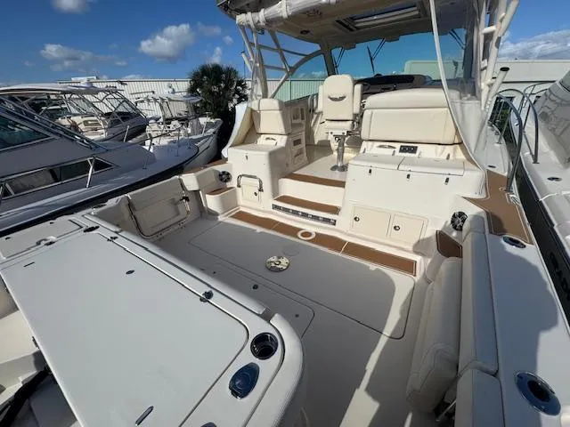 Slide: The Image of 2021 Grady-White Express 370 boat interior with seating and helm, docked under blue sky. - 5