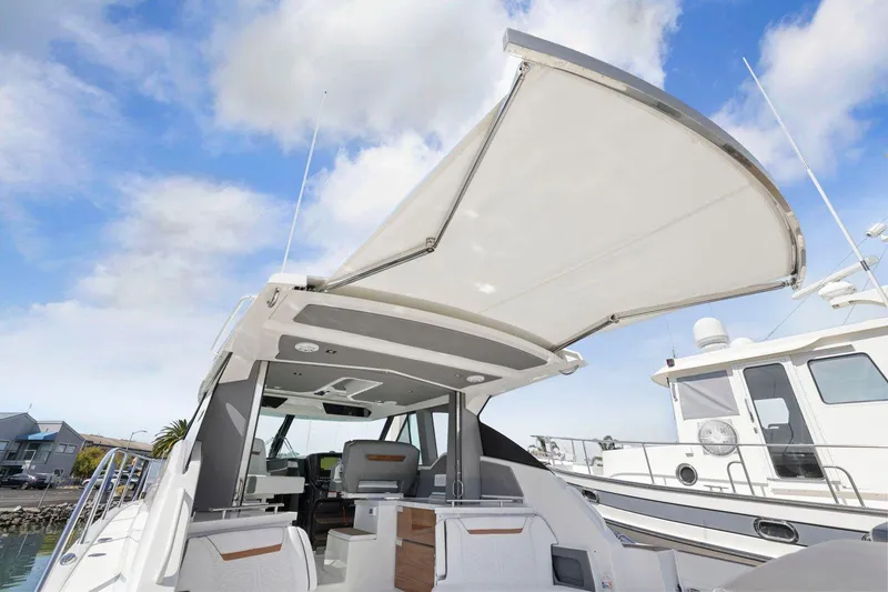 Slide: The Image of 2022 Tiara Yachts 43 LE with open canopy, docked under blue sky. - 19