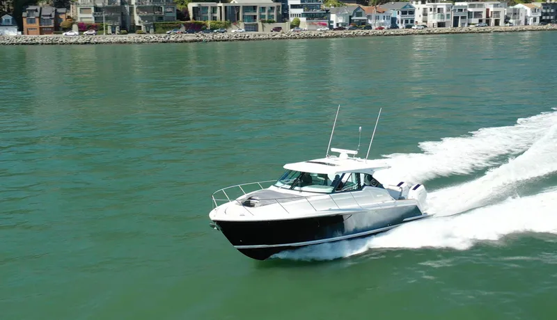 Slide: The Image of 2022 Tiara Yachts 43 LE cruising on a calm waterway near coastal homes. - 3