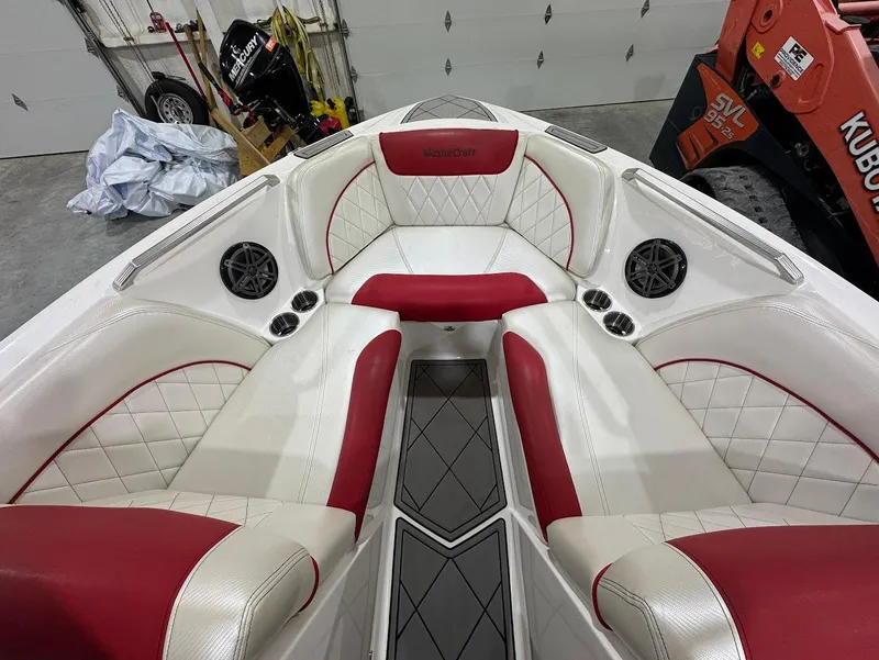 Slide: The Image of 2013 MasterCraft X30 boat interior with red and white seating, diamond stitching, and speakers. - 18