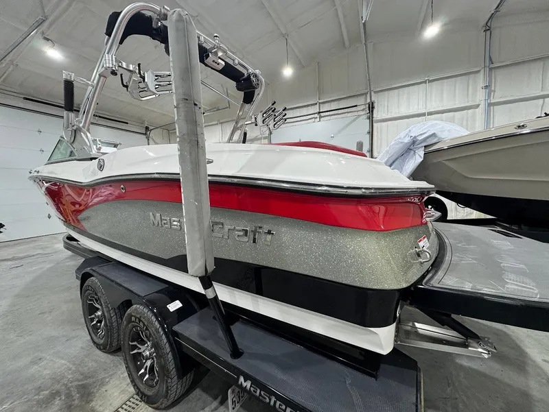 Slide: The Image of 2013 MasterCraft X30 boat in a garage, red and white design on a trailer. - 2