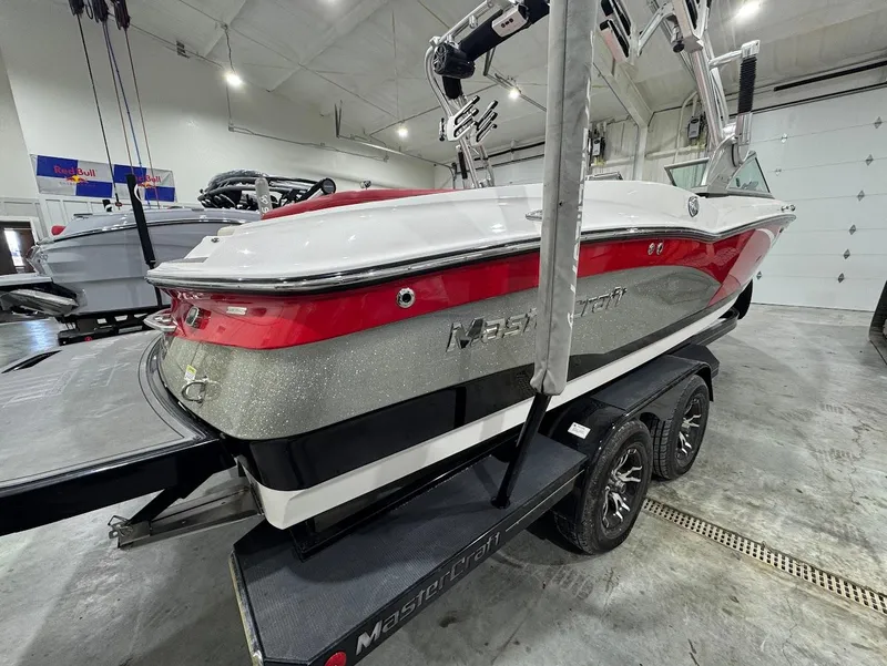 Slide: The Image of 2013 MasterCraft X30 boat in showroom, red and white design, on trailer. - 4